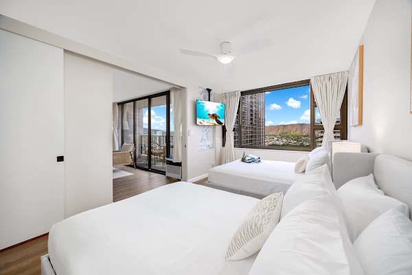 Unwind in this breezy bedroom featuring a queen bed, a full bed, and a 50" smartTV, perfect for relaxing after a sun-soaked day.