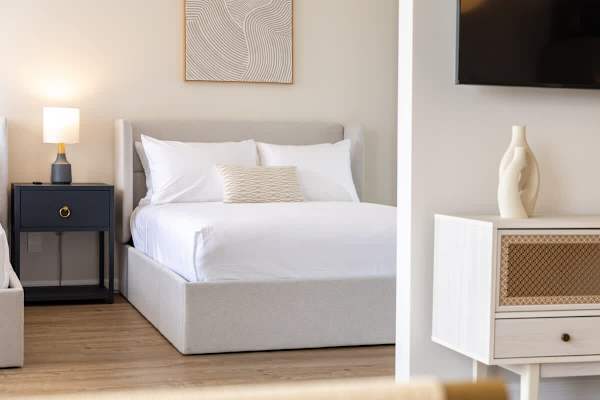 Drift into a peaceful sleep in this inviting bedroom, featuring a plush bed, a stylish nightstand with a warm lamp, and elegant decor.