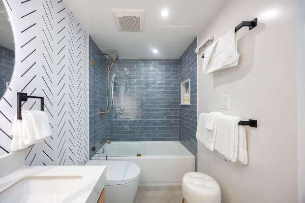 Enjoy a relaxing bath or a refreshing shower in this sleek bathroom, featuring a modern tub/shower combo and a beautiful herringbone tile accent wall.