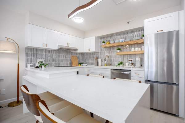 Prepare a delicious meal in this fully equipped, modern kitchen, featuring a large quartz breakfast bar and sleek stainless steel appliances.