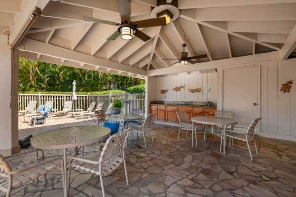 Enjoy a shaded break or an outdoor meal in the covered pavilion area, complete with ceiling fans for comfort, ample patio seating, a convenient wet bar/counter space, and easy access to the nearby pool deck.
