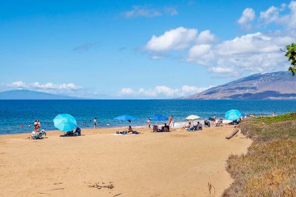 Stroll just moments from your door to enjoy a perfect day on the sandy beach, where you can relax under your umbrella, swim in the sparkling blue water, and take in the magnificent mountain and island views.