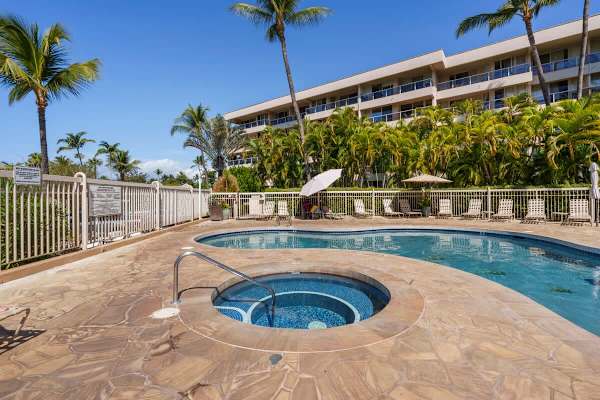 Dip into the soothing hot tub set in the beautifully paved stone deck, surrounded by lounge chairs and swaying palm trees, perfect for unwinding after a long day of island adventures.