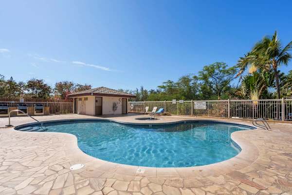 Dip into the sparkling blue water of the on-site swimming pool, featuring a lovely stone deck, a relaxing hot tub nearby, and a convenient BBQ area perfect for enjoying sunny afternoons amidst the tropical foliage.