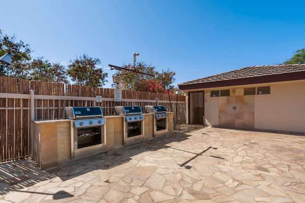 Grill your favorite meals at the spacious outdoor BBQ station, featuring multiple modern gas grills set in a beautiful stone area.