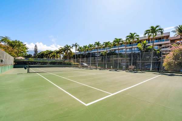Grab your racket and enjoy a friendly match on the well-maintained on-site tennis court, surrounded by lush tropical landscaping under a beautiful sunny sky.