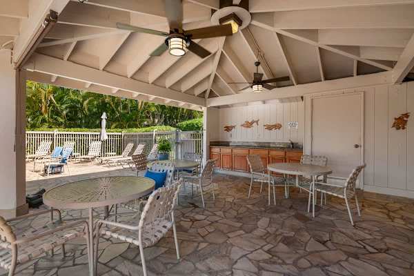 Enjoy a shaded break or an outdoor meal in the covered pavilion area, complete with ceiling fans for comfort, ample patio seating, a convenient wet bar/counter space, and easy access to the nearby pool deck.