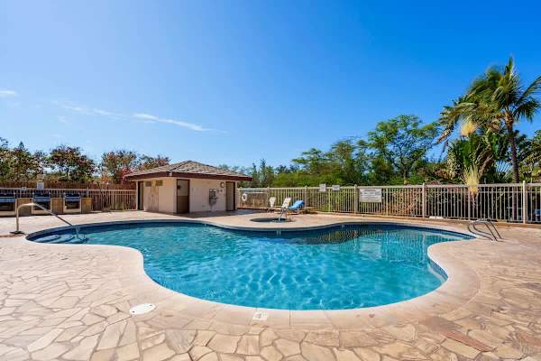 Dip into the sparkling blue water of the on-site swimming pool, featuring a lovely stone deck, a relaxing hot tub nearby, and a convenient BBQ area perfect for enjoying sunny afternoons amidst the tropical foliage.