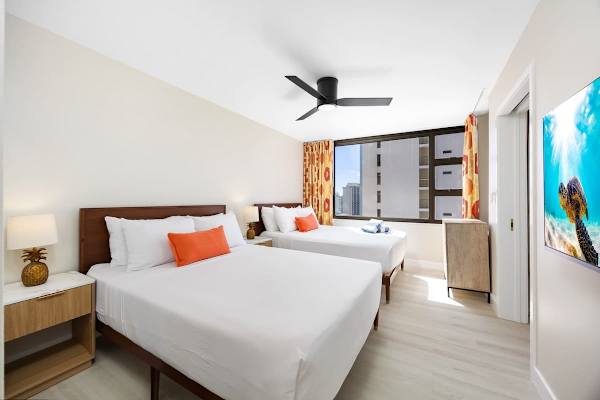 Enjoy a peaceful night's sleep in this bright bedroom, perfectly set up with 2 Queen beds, a ceiling fan for comfort, and a lovely view of the city and a peek of the ocean from the window!