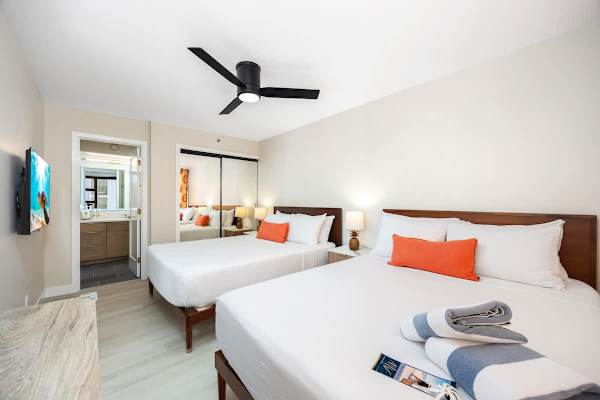 This bedroom features 2 cozy Queen beds, storage with mirrored closet doors, a mounted 40" Sony TV for relaxing, and direct access to your modern private bathroom!