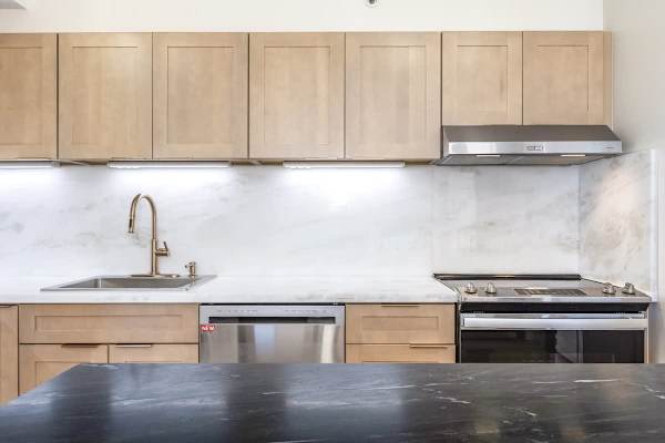 Your beautifully designed kitchen area combines light wood cabinetry with a bright marble-look backsplash, offering a modern stovetop and oven, a convenient dishwasher, and a sleek sink and faucet for all your cooking needs!