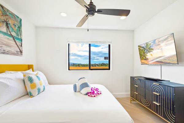 Drift off in this bright, modern primary bedroom, featuring a comfortable queen bed, stylish tropical accents, and a 43" Roku TV for ultimate nighttime relaxation.