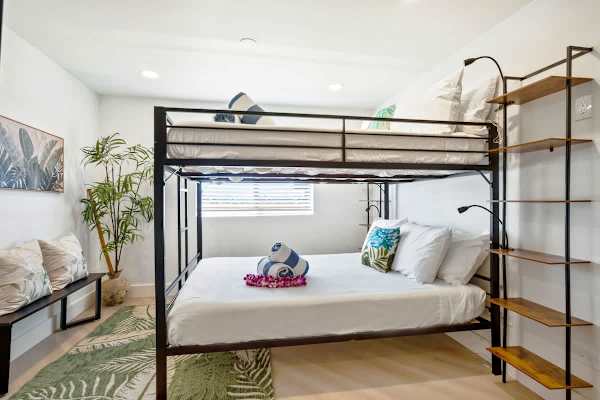 Perfect for families or groups, the secondary bedroom features a queen-over-queen metal bunk bed, wall-mounted 43" TV, and split AC, offering comfortable and cool shared sleeping space.