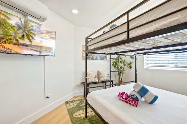 Perfect for families or groups, the secondary bedroom features a queen-over-queen metal bunk bed, wall-mounted 43" TV, and split AC, offering comfortable and cool shared sleeping space.