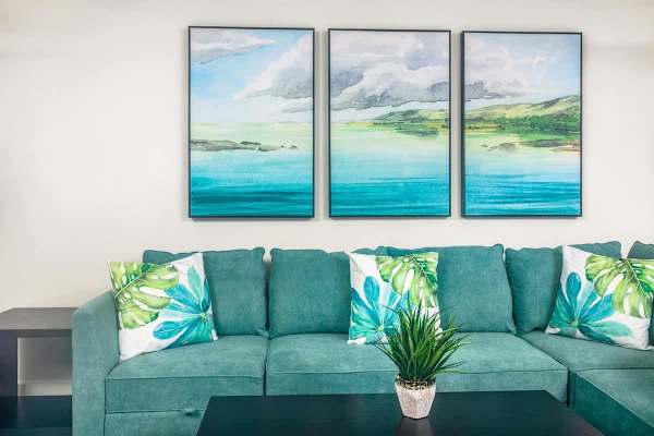 Relax in style on the deep, comfortable teal sectional sofa, accented by beautiful watercolor island art pieces.