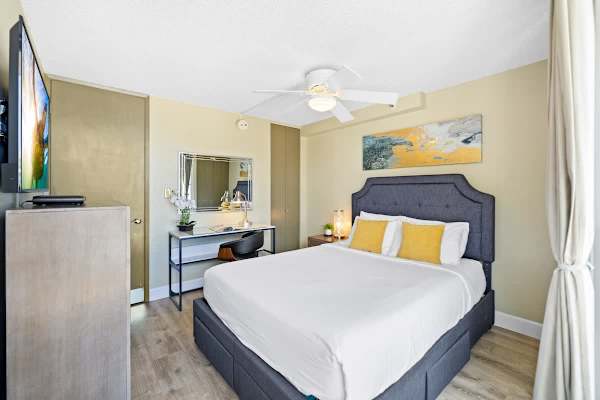 Bedroom with queen-size bed, ceiling fan, TV, dedicated workspace, and closet.