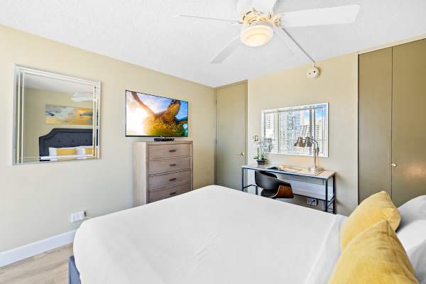 Bedroom with queen-size bed, ceiling fan, TV, dedicated workspace, and closet.