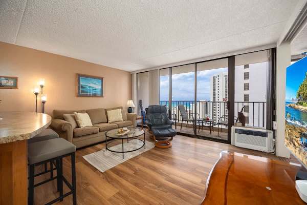 The living room has a pull-out sleeper sofa, a reclining chair, a coffee table, a window AC, a 40" smart TV, and direct access to the balcony!