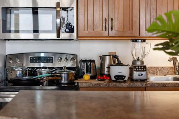Prepare delicious meals in this fully equipped, modern kitchen, featuring sleek stainless steel appliances including a microwave, oven, and refrigerator, and small appliances like a toaster, kettle, and blender.