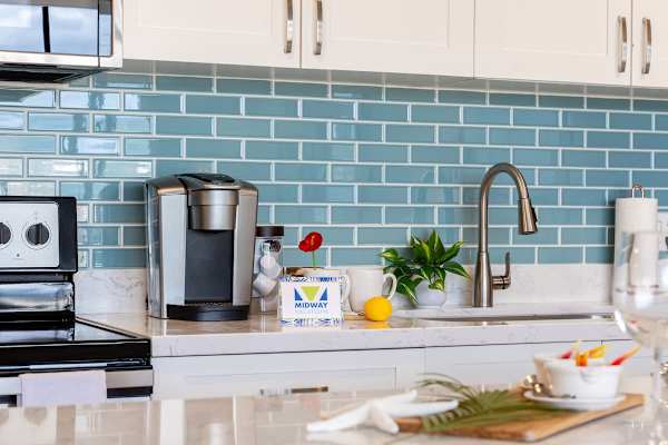 Modern kitchen countertop with a coffee maker and blue tile backsplash