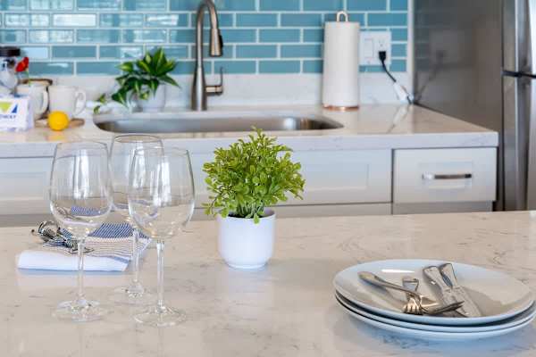 Modern kitchen countertop with glassware and a small plant against a blue tile backsplash