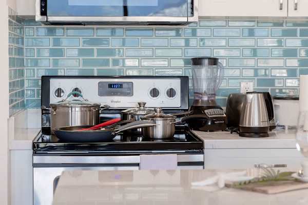 Modern kitchen stove with stainless steel cookware and blue tile backsplash