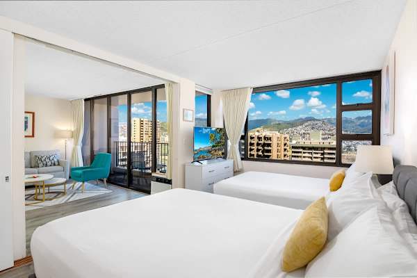 Bright room with two beds and city views through large windows