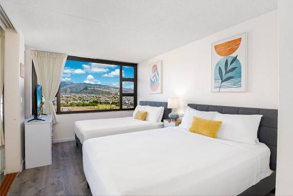 Bright bedroom with two queen beds and a large window showcasing mountain views.