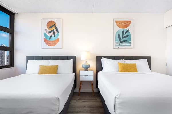 Bright bedroom with two queen beds and modern abstract art.