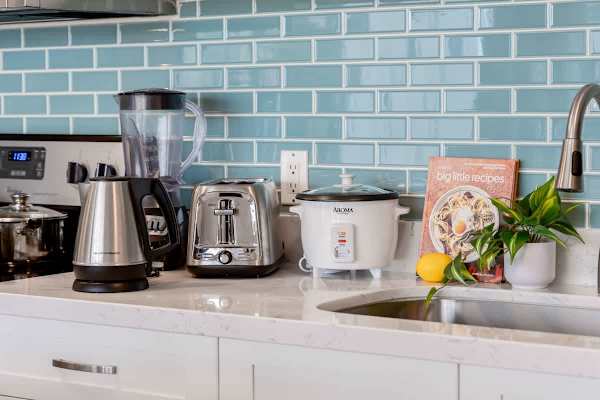 Modern kitchen counter with essential appliances and a blue tile backsplash.