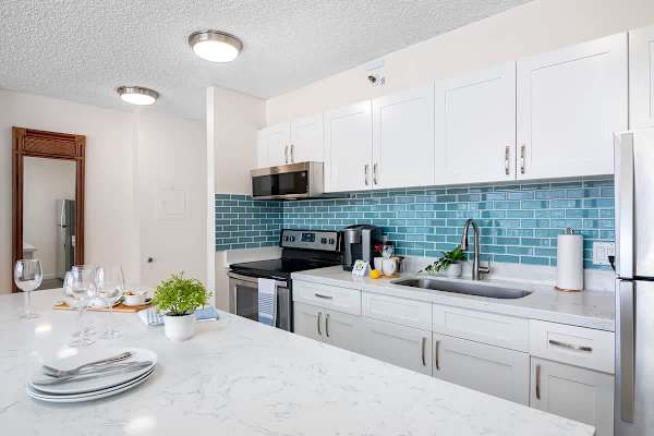 Modern kitchen with white cabinetry and blue tile backsplash