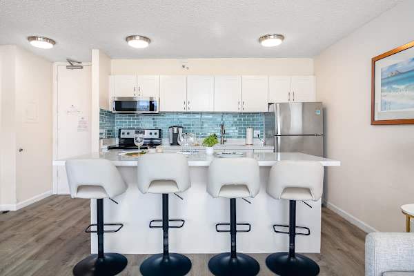 Modern kitchen with a blue tile backsplash and seating for four at the island