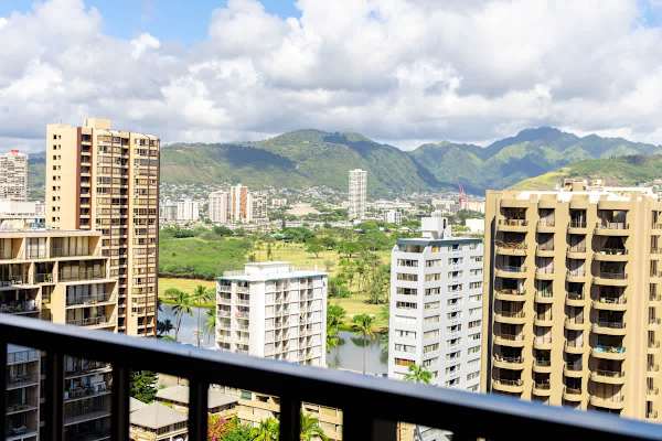View of city buildings and green mountains from a balcony