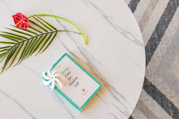 A modern marble table with a decorative book and tropical leaf accent.