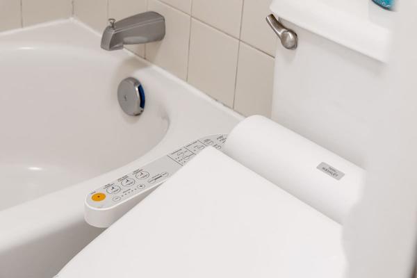 Modern bathroom featuring a high-tech bidet toilet seat next to a clean bathtub.