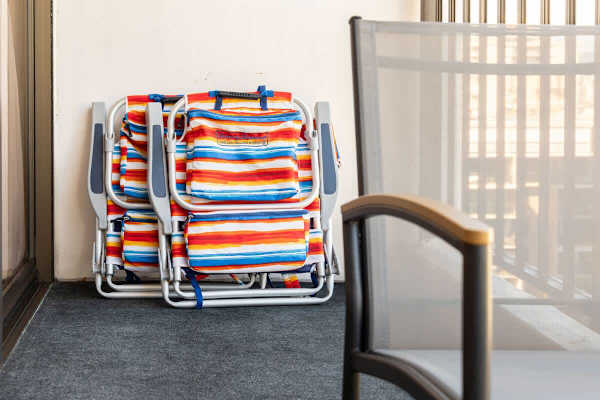 Folded colorful beach chairs stored on a balcony with outdoor seating.