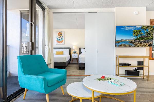 Modern living area with a turquoise armchair and sliding doors leading to the bedroom