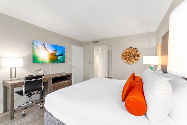 Bedroom with king-size bed, a dedicated workspace, flatscreen TV, and access to the bathroom.