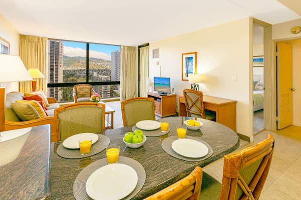 Bright living and dining area with city and mountain views through large windows.