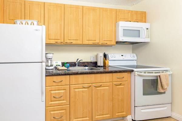 Compact kitchen with light wood cabinets and essential appliances for convenient cooking.