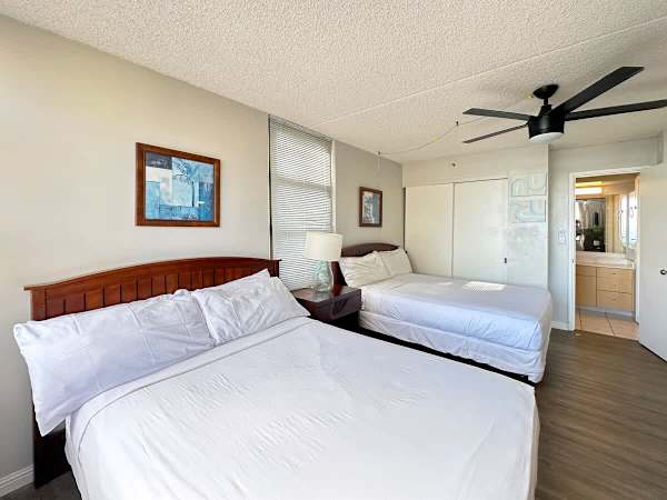 The bedroom with 2 full-size beds, a closet, a ceiling fan, and access to the bathroom.