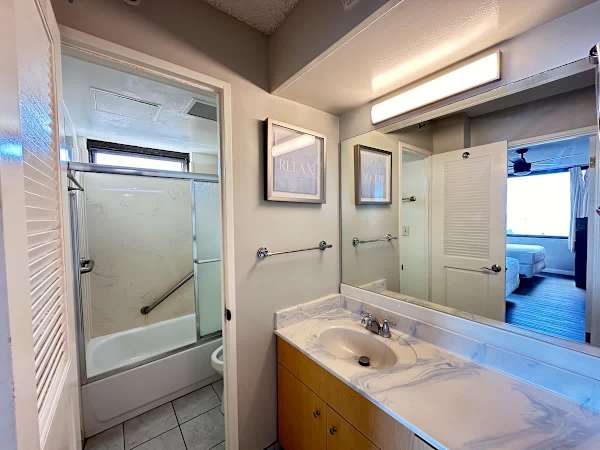 The full bathroom with tub and shower combo, and a vanity with cabinet.