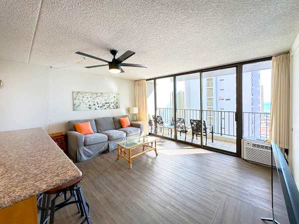 Living with pull-out sleeper sofa, coffee table, ceiling fan, air-conditioning, and a flat-screen TV.