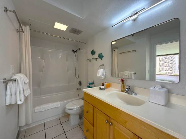 A bright and clean full bathroom featuring a bathtub/shower combination, and a light wood vanity.