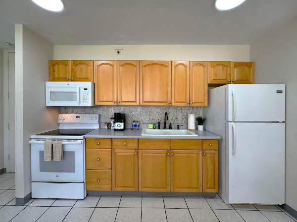 A bright and fully-equipped kitchen featuring ample light wood cabinets, a refrigerator, and a stove/microwave set, perfect for preparing meals during your stay!