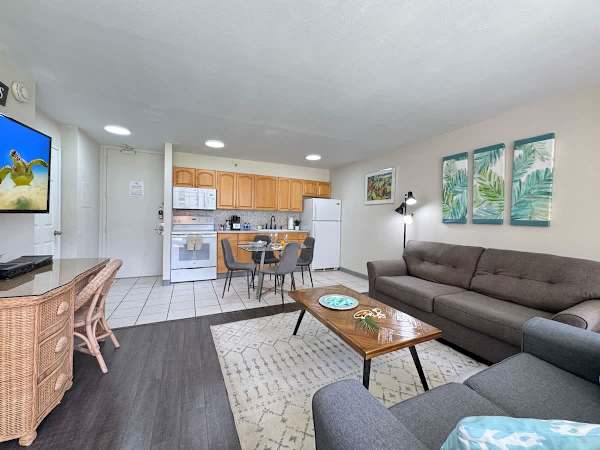 A bright and comfortable living area, featuring a spacious living area and a connected full kitchen with a dining nook.