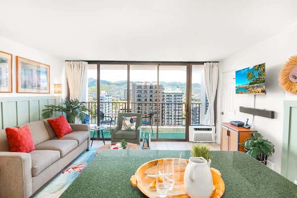 Living room with pull-out sleeper sofa, accent chair, coffee table, air conditioner, and mountain view.