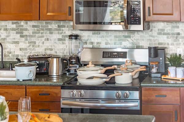 Full-size appliances and kitchen utensils are ready for your cooking session.