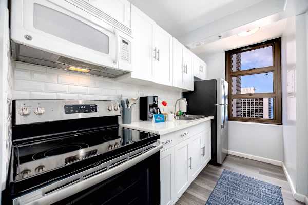 Prepare your favorite meals in this well-appointed kitchen, featuring modern white cabinetry, essential appliances including a GE microwave and electric range, and ample counter space for your culinary needs.