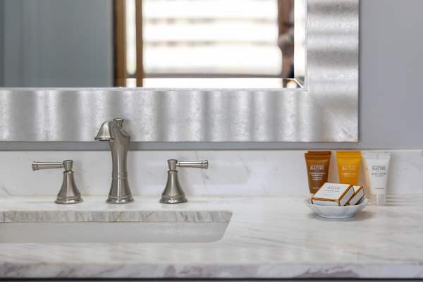 The bathroom features a sleek vanity with starter pack toiletries and a spacious marble countertop for your convenience.